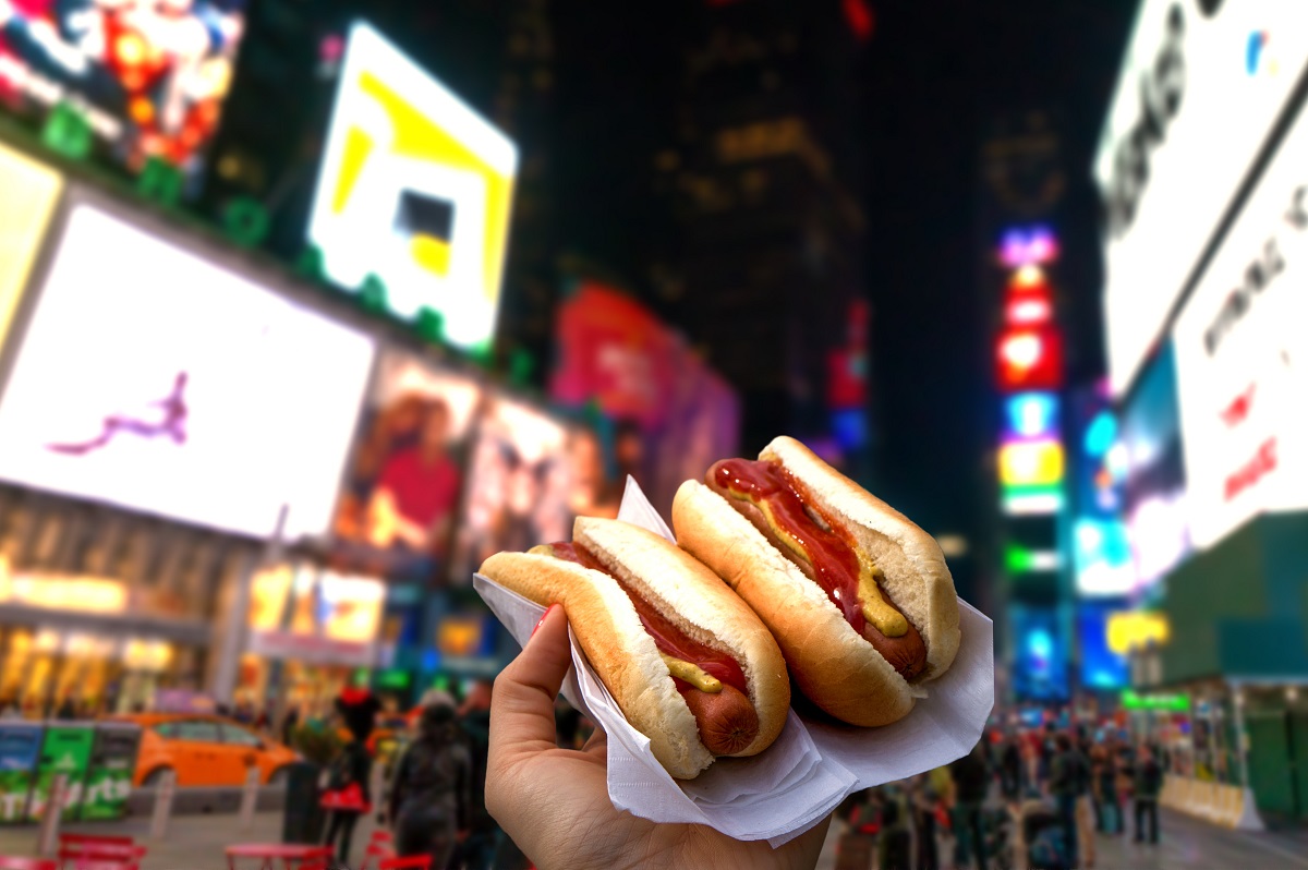 Holding two hot dogs in NYC on the Times Square