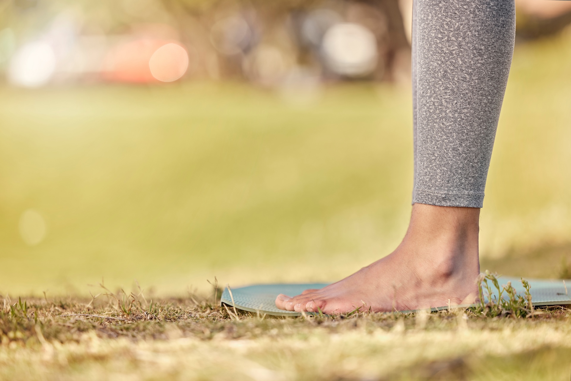 Woman feet, mat and yoga on grass, park and exercise, meditation and spiritual wellness in nature f