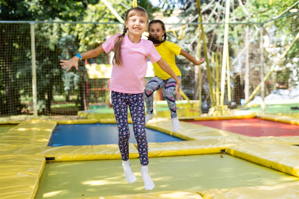 two girls jumping on a trampoline on a summer day