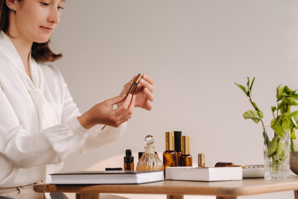 The aromatherapist girl is sitting in her office and holding a bottle of aromatic oils. there are essential oils on the table