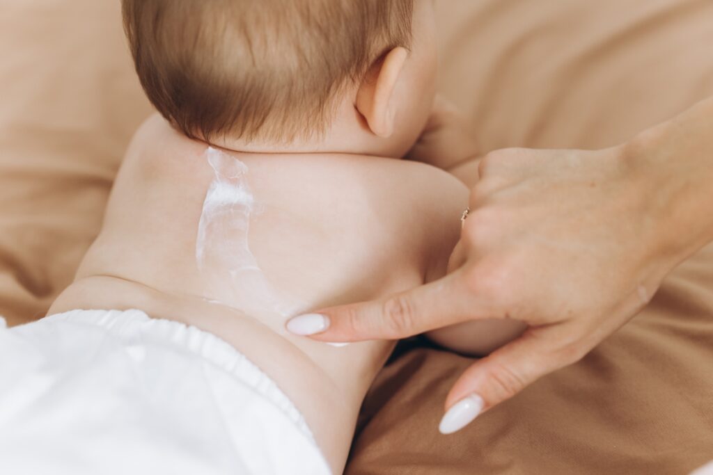 Happy mother applying cream on her baby girl's body