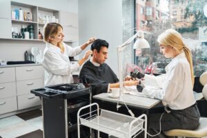 Beauty parlour visitor with smartphone having his hair cut