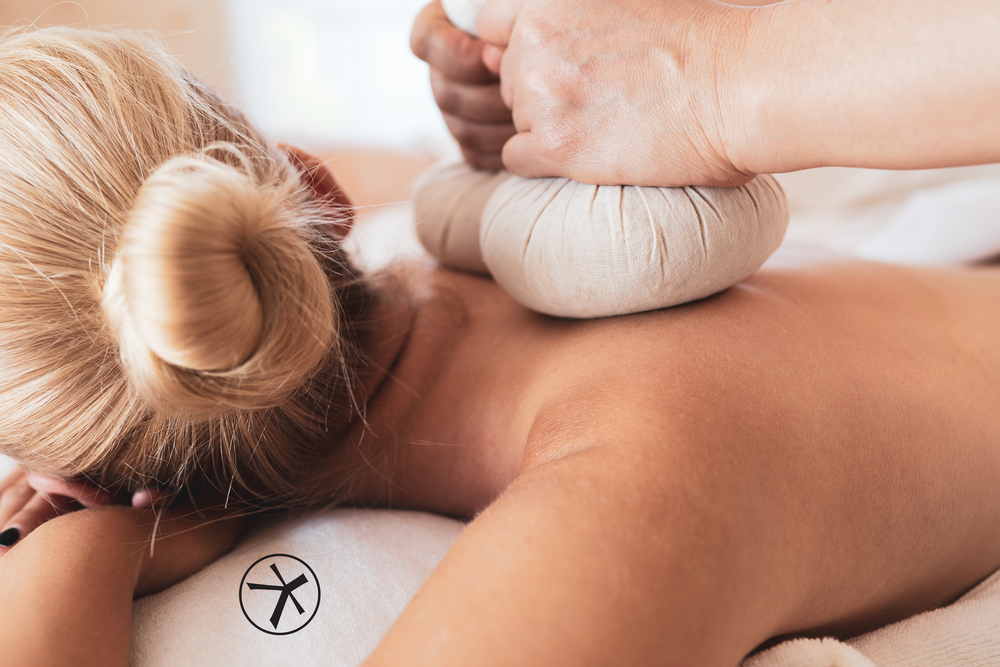 Close up of masseuse hands grab the warm herbal ball to press massage over the woman back for deeply therapy comforting and relaxing, Thai massage is the famous in Thailand for tourist.