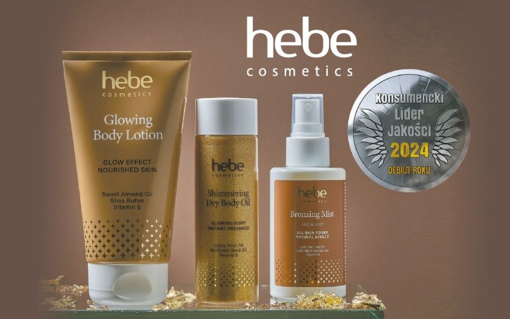 Produkty Hebe Cosmetics, w tym Glowing Body Lotion, Shimmering Dry Body Oil oraz Bronzing Mist, zaprezentowane na tle brązowego gradientu. Obok znajduje się odznaczenie „Konsumencki Lider Jakości 2024 – Debiut Roku”, wyróżniające markę za wysoką jakość. Produkty otoczone są złotymi dekoracjami, podkreślającymi ich luksusowy charakter.